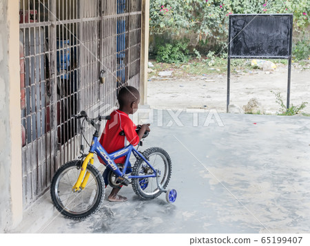 Dark-skinned boy with bicycle 65199407