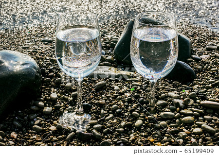 Two glasses of water on sea by water Two glasses of water on sea by water 65199409