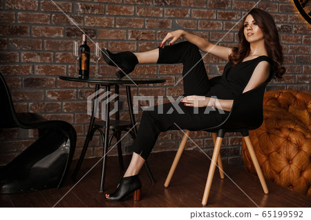 Glamour sexy young confident woman with long hair sitting with legs on table 65199592