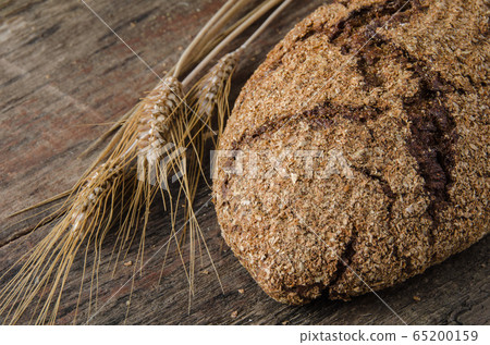 The spikelets and baked bread on a wooden background The spikelets and baked bread on a wooden background 65200159
