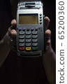Credit card reader isolated on black background. Pos apparatus for non-cash contactless payment. A man holds an NFC terminal in his hands 65200360