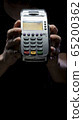 Credit card reader isolated on black background. Pos apparatus for non-cash contactless payment. A man holds an NFC terminal in his hands 65200362