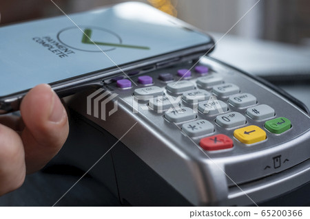 NFC - Near field communication, mobile payment. Bank terminal for non-cash payment by mobile phone or credit card. The buyer applies the phone, makes a purchase on the Internet NFC - Near field communication, mobile payment. Bank terminal for non-cash payment by mobile phone or credit card. The buyer applies the phone, makes a purchase on the Internet 65200366