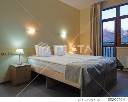 Room with a double bed with table and wall lights 65200924