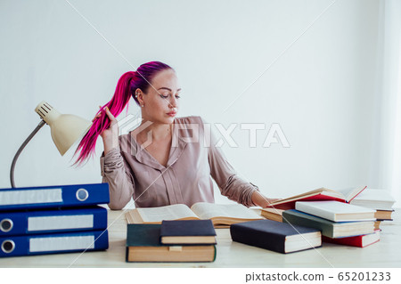 girl with pink hair sitting at a table reading a book girl with pink hair sitting at a table reading a book 65201233