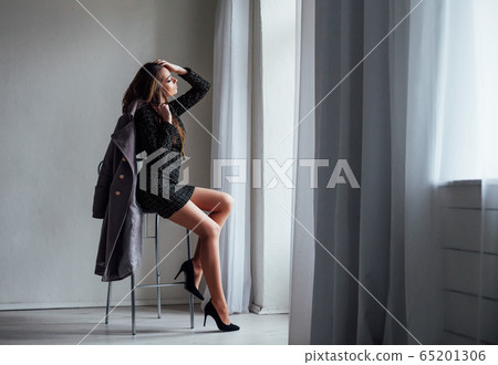 girl with gray coat sits on a Chair looking out of the window girl with gray coat sits on a Chair looking out of the window 65201306