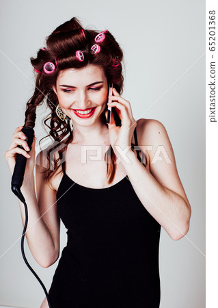girl with hair curlers talking on the phone and makes the hairstyle 65201368