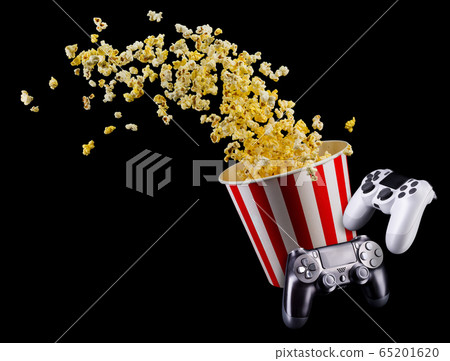 Flying popcorn and video game joystick gamepad isolated on a black 65201620