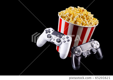 Flying popcorn and video game joystick gamepad isolated on a black 65201621