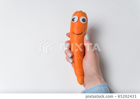 Carrot with funny face in hand on white Carrot with funny face in hand on white 65202431