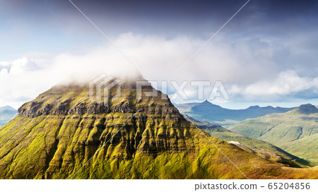 Foggy mountain peaks and clouds covering sea and mountains 65204856