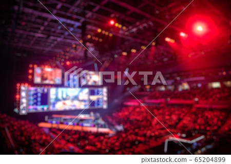 Blurred background of an esports event - Main stage venue, big screen and lights before the start of the tournament. Blurred background of an esports event - Main stage venue, big screen and lights before the start of the tournament. 65204899