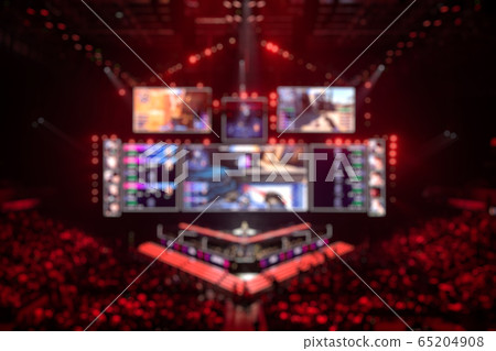 Blurred background of an esports event - Main stage venue, big screen and lights before the start of the tournament. Blurred background of an esports event - Main stage venue, big screen and lights before the start of the tournament. 65204908