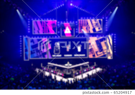 Blurred background of an esports event - main stage venue, big screen and lights before the start of the tournament. 65204917
