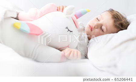 Baby girl sleeping with her unicorn. Close up. 65206441