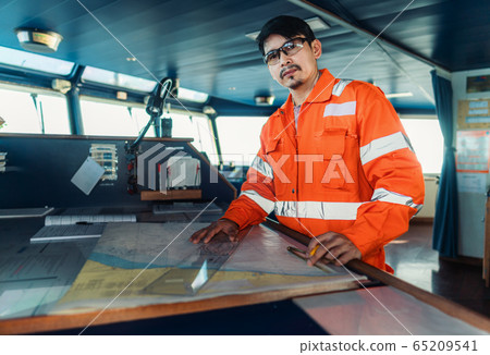 Filipino deck Officer on bridge of vessel or ship. He is plotting position on chart 65209541
