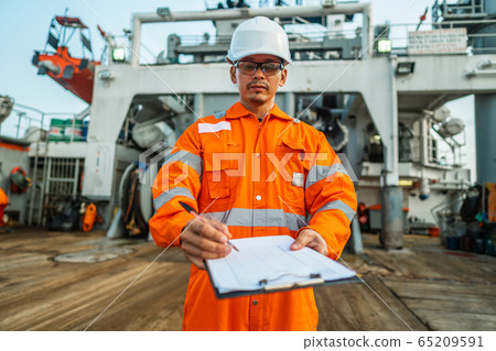 Filipino deck Officer on deck of offshore vessel or ship fills checklist. Paperwork at sea 65209591