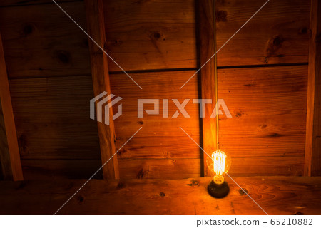 Lighted incandescent light bulb in a wooden house 65210882