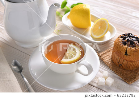 Cup of tea with lemon and cupcake on white table Cup of tea with lemon and cupcake on white table 65212792