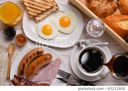 Pouring coffee on a cup with breakfast on wooden table 65212808
