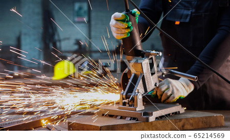 Worker using a grinder to cut the metal detail 65214569