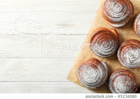 Cinnamon rolls and baking paper on white wooden Cinnamon rolls and baking paper on white wooden 65216080