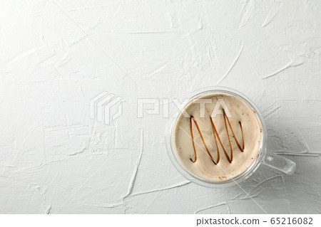 Glass cup of foamy latte with caramel on white Glass cup of foamy latte with caramel on white 65216082