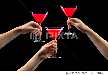 Set of hands holding strawberry martini glass isolated on black. 65220660