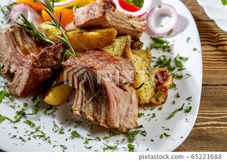Grilled rack of lamb with fried potatoes and fresh vegetables. Dinner at restaurant. Grilled rack of lamb with fried potatoes and fresh vegetables. Dinner at restaurant. 65221688