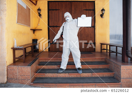 Coronavirus Pandemic. A disinfector in a protective suit and mask sprays disinfectants in the house or office Coronavirus Pandemic. A disinfector in a protective suit and mask sprays disinfectants in the house or office 65226012