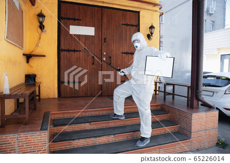 Coronavirus Pandemic. A disinfector in a protective suit and mask sprays disinfectants in the house or office Coronavirus Pandemic. A disinfector in a protective suit and mask sprays disinfectants in the house or office 65226014
