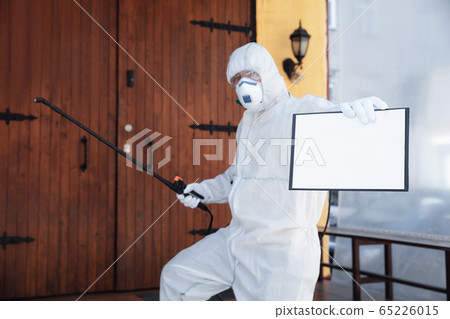 Coronavirus Pandemic. A disinfector in a protective suit and mask sprays disinfectants in the house or office Coronavirus Pandemic. A disinfector in a protective suit and mask sprays disinfectants in the house or office 65226015