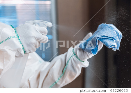 Coronavirus Pandemic. A disinfector in a protective suit and mask sprays disinfectants in the house or office Coronavirus Pandemic. A disinfector in a protective suit and mask sprays disinfectants in the house or office 65226023