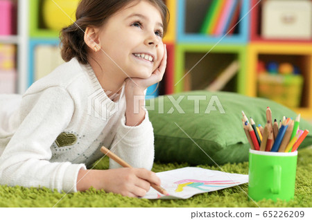 Little girl drawing with pencil in her room while lying on floor 65226209