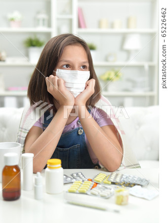 Portrait of little girl wearing facial mask with pills 65226462