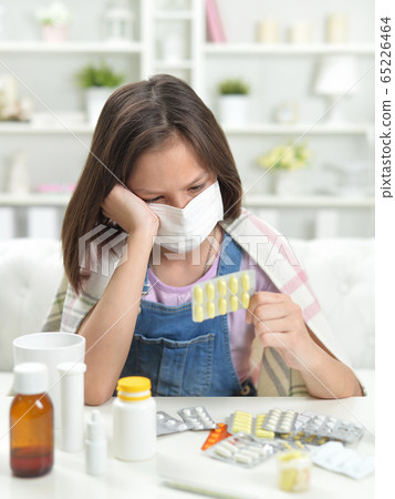 Portrait of little girl wearing facial mask with pills 65226464