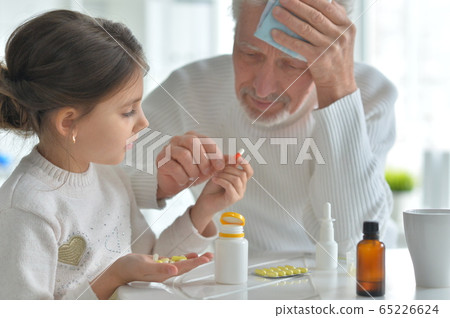 Granddaughter giving medicine to her grandfather in room Granddaughter giving medicine to her grandfather in room 65226624
