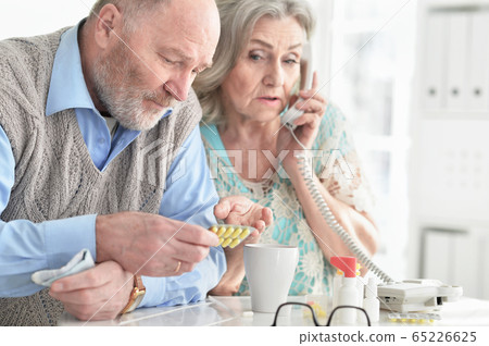 Portrait of ill senior couple at home calling doctor 65226625