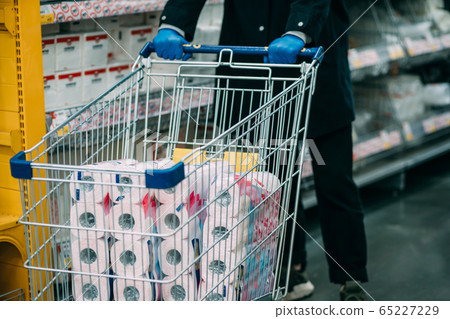 Man in protective gloves buying toilet paper in shop. Man in protective gloves buying toilet paper in shop. 65227229