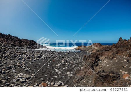 Beach with black volcanic sand, stones and rocks with ocean at Lanzarote, Spain. Beach with black volcanic sand, stones and rocks with ocean at Lanzarote, Spain. 65227381