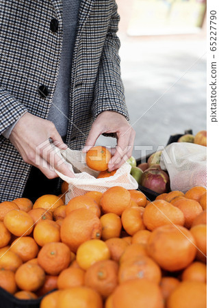 man using a reusable mesh bag at a greengrocer 65227790