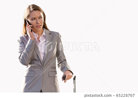 Cutouts of Young attractive businesswoman talking on smartphone while holding suitcase Cutouts of Young attractive businesswoman talking on smartphone while holding suitcase 65228707
