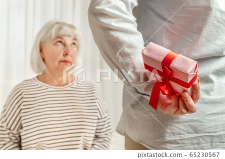 Happy mother's day. Daughter holds surprise gift box to give mom Happy mother's day. Daughter holds surprise gift box to give mom 65230567