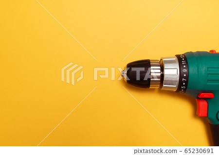 One cordless drill with drills, also working as a screwdriver on yellow background. Mininmalistic flat lay. One cordless drill with drills, also working as a screwdriver on yellow background. Mininmalistic flat lay. 65230691