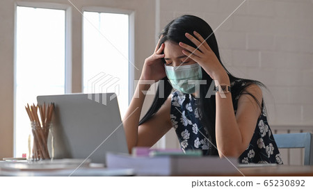 Young woman that infected a covid-19 virus(corona virus) using laptop and sitting at the table. 65230892