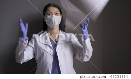 Happy doctor rejoices ending of pandemic. Beautiful female medical worker laughs throwing up paper medical forms standing on gray background Happy doctor rejoices ending of pandemic. Beautiful female medical worker laughs throwing up paper medical forms standing on gray background 65231514