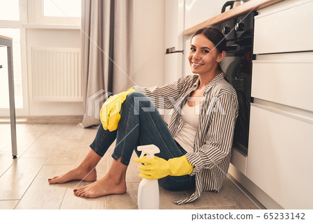 Delighted brunette woman making pause during cleaning 65233142