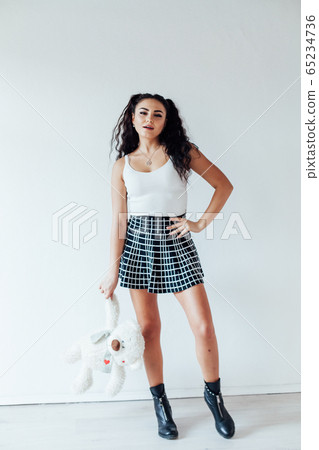 Beautiful fashionable brunette woman in a skirt with toy bear Beautiful fashionable brunette woman in a skirt with toy bear 65234736