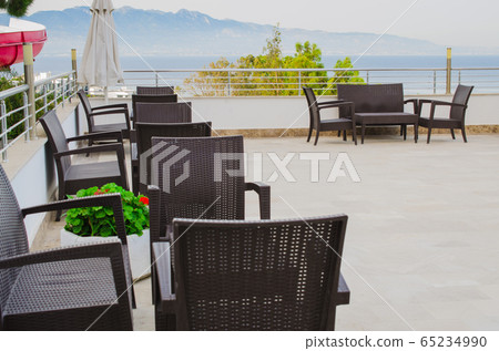 Wicker tables and chairs on the terrace of a cozy summer cafe. Wicker tables and chairs on the terrace of a cozy summer cafe. 65234990
