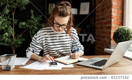 Happy millennial woman taking notes in notepad 65237192